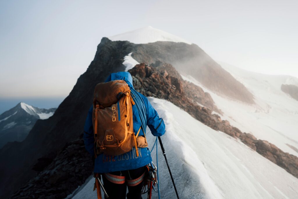 A person scaling a large snowy mountain.